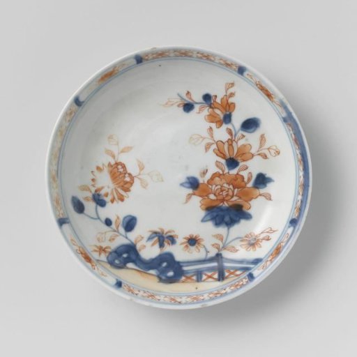 Saucer with flower sprays behind a rock and fence