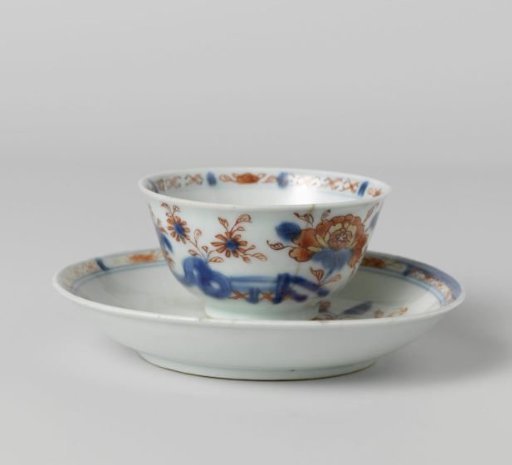 Cup and saucer with flower sprays behind a rock and fence