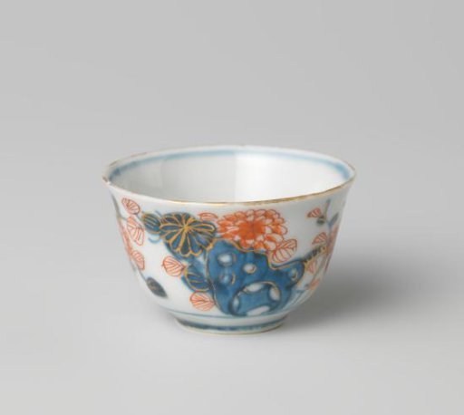 Cup with butterflies and flowering plants near a rock