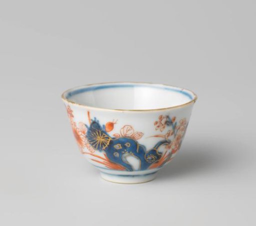 Cup with butterflies and flowering plants near a rock
