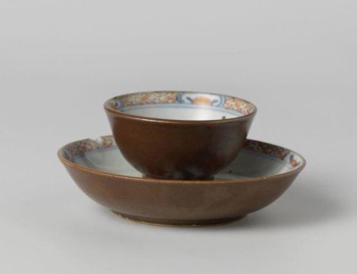 Cup and saucer with flowering plants near a rock