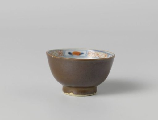 Cup with flower sprays near a rock and a dark brown glaze
