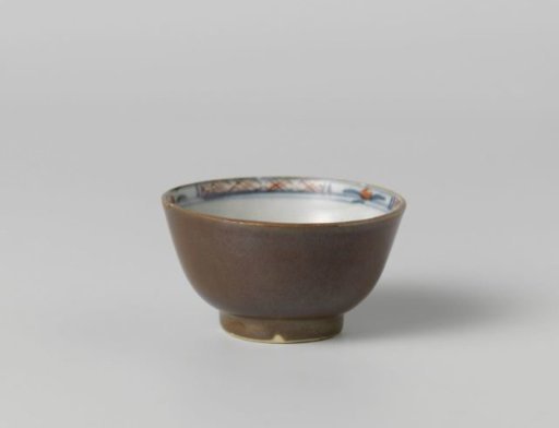 Cup with flower sprays near a rock and a dark brown glaze