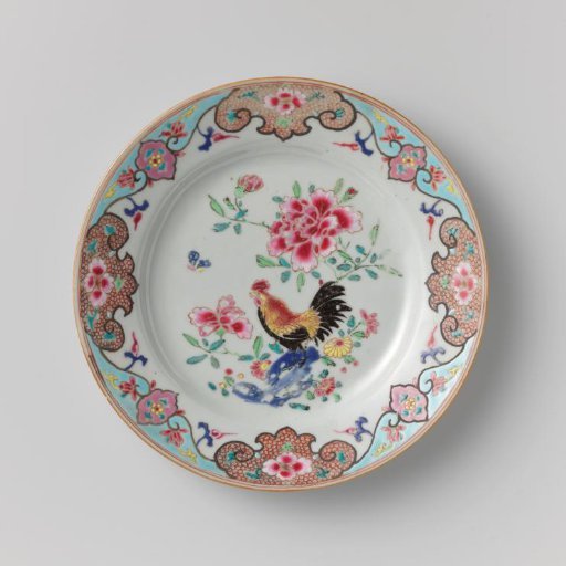 Plate with a cock on a rock near flowering plants