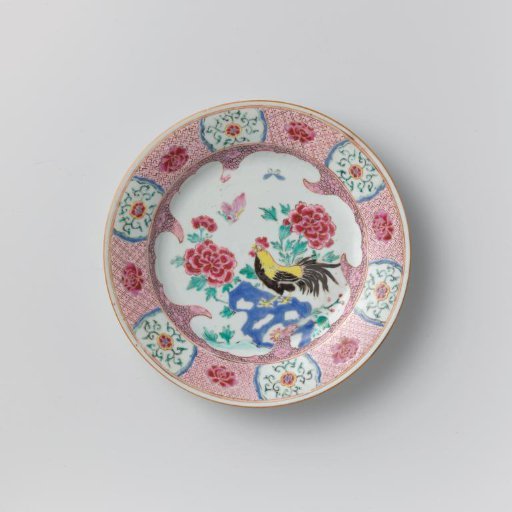 Plate with a cock on a rock near flowering plants