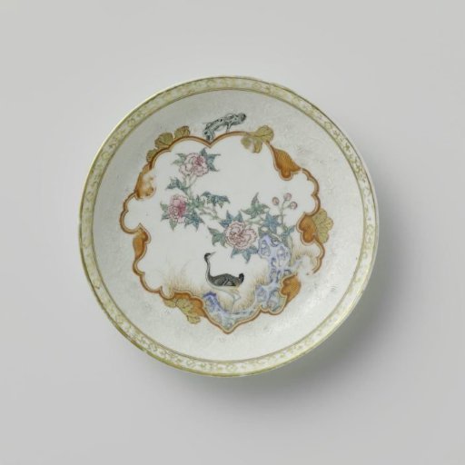Saucer with a crane near a peony plant and rock
