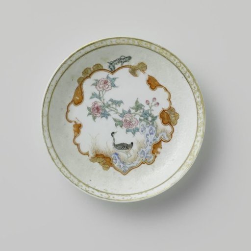 Saucer with a crane near a peony plant and rock