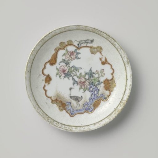Saucer with a crane near a peony plant and rock