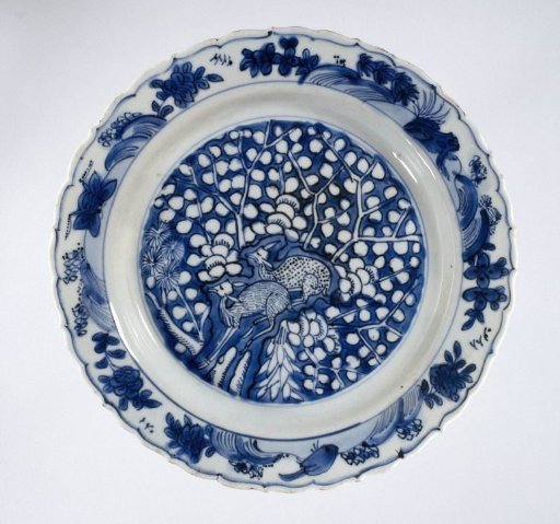 Plate with two deer near a rock and flowering trees
