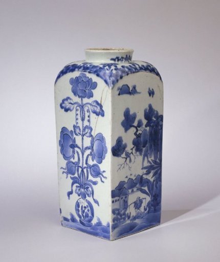 Square bottle with figures in a landscape, a flower vase and a flowering plant near a rock