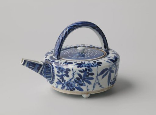 Kettle on three small legs with rocks and flowering plants