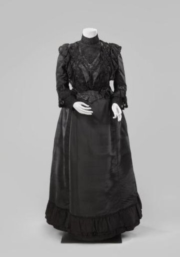 Skirt of black silk, finished at the bottom with passementerie, three strips of crêpe and a fringe; black silk lining, finished at the bottom with a taffeta pleated strip.