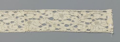 Strip of bobbin lace with a wavy flower vine
