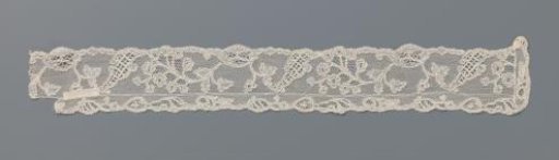 Strip of bobbin lace with a flower branch full of rosettes