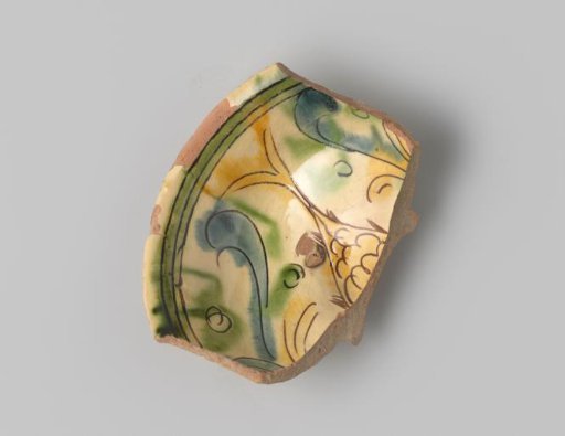 Plate fragment with red-fired body, with a depiction of a fish tail, curls and circles in sgraffito technique and white, yellow, blue and green glaze on the front