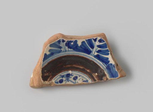Fragment of a plate with a red-firing sherd, with white glaze on the front and back, decorated on the front with half-circle leaf forms, a half-circle and a diamond pattern in blue and purple glaze