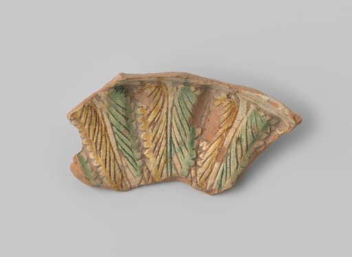 Sherd of red-firing earthenware, decorated on the front with a leaf motif in sgraffito technique with white, yellow, and green glaze, unglazed on the back