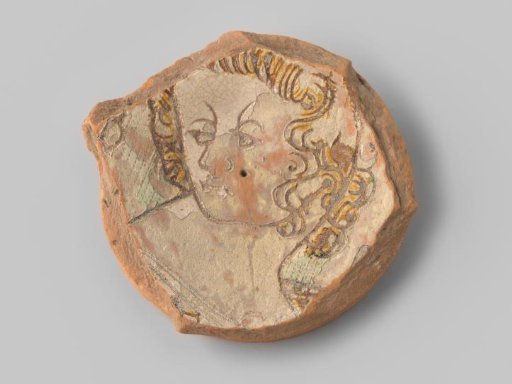 Fragment (foot) with red sherd, in sgraffito technique a man's head turned to the left with ochre-coloured curly hair, green dotted background