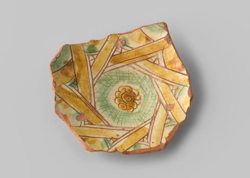 Fragment (foot) with red sherd, in sgraffito drawing a flower with a wreath of angular shapes in ochre and green around it