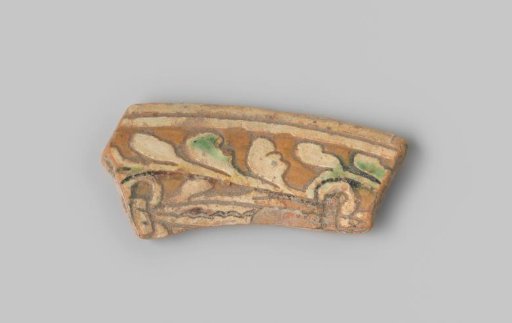 Fragment of earthenware with a reddish sherd, decorated on the front with a leaf vine in sgraffito technique, partially glazed white on the front, and glazed white on the back
