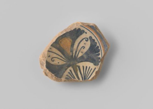 Fragment (foot) with reddish sherd, on the front side provided with a cross shape in blue and yellow glaze on a white background