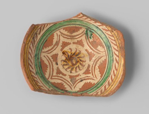Fragment of red-firing earthenware with a foot ring, glazed with a geometric pattern in sgraffito technique in white, yellow and green glaze on the upper side, unglazed on the underside