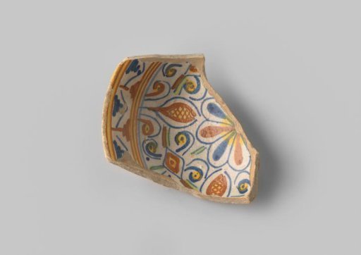 Fragment (foot) with a white sherd, with flowers, stripes and geometric planes in yellow, orange and blue glaze on a white background on the upper side
