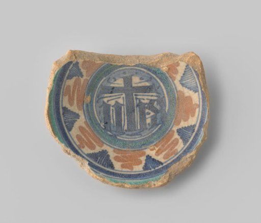 Fragment (foot) with reddish sherd; within several blue and green circles, a fleetly painted Jesus monogram in blue on a white ground in the center, surrounded by a broad band with angular motifs in blue and orange