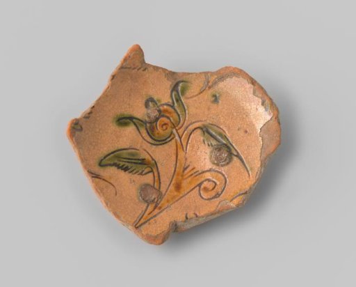 Fragment with a red sherd, decorated on the upper side with a flower in sgraffito technique with yellow and green glaze