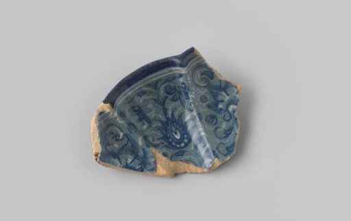 Fragment of a ribbed and scalloped rim with reddish sherd, on a grey-blue ground in blue and opaque white a decoration of plant motifs, on the back blue crosses