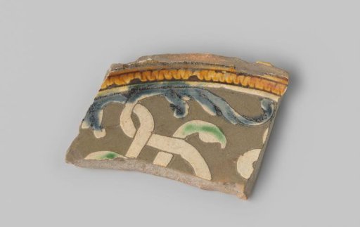 Fragment of grey-fired earthenware, decorated in sgraffito technique with floral scrolls in white, blue, green and orange