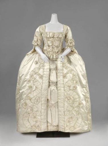 Skirt of cream-colored silk with pleated silk strips, finished with narrow passementerie and light blue silk loops; the skirt is heavily pleated at the side slits.