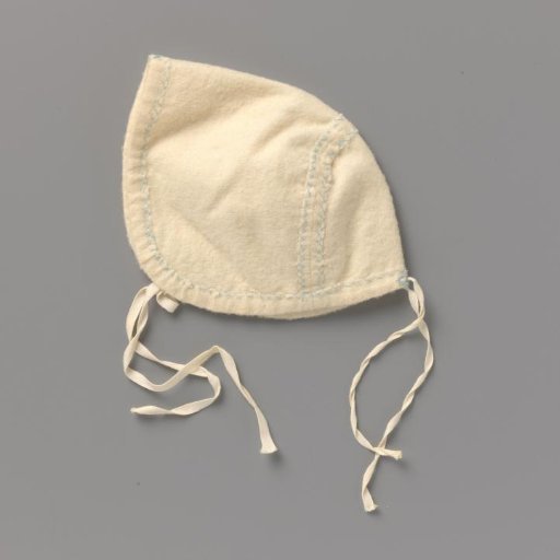 Children's cap with a drawstring, through which two ribbons are threaded, of white wool, decorated with a blue flannel stitch; two ribbon bows at the back and front