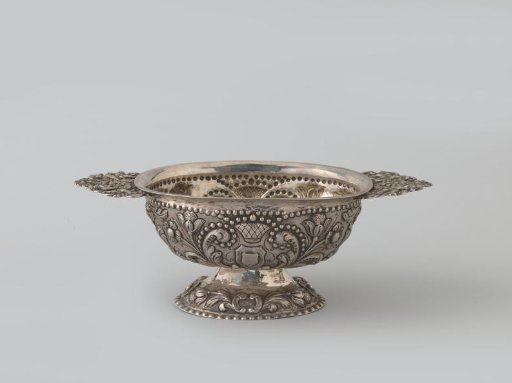 Silver repoussé brandy bowl. Oval cup on arched foot. Openwork horizontal handles. False.
