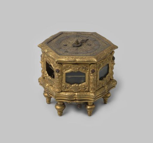 Table clock decorated with shell forms and masks
