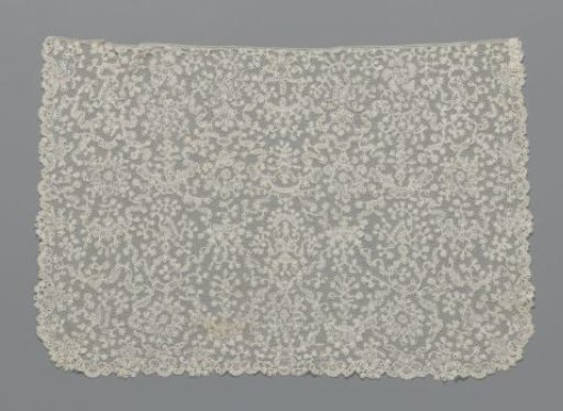 Cufflink from bobbin lace with a symmetrical pattern of candelabras or flower baskets surrounded by garlands of volutes