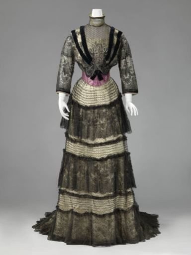 Bodice of cream silk, under black lace with flowers and circles, black velvet bands and paillettes and silver-colored paillettes and beads; purple pleated sash.