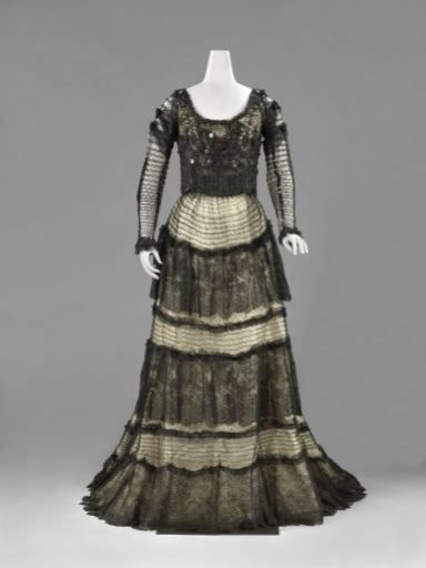 Skirt with train of cream satin under black lace, decorated with gathered strips of black lace with floral motifs