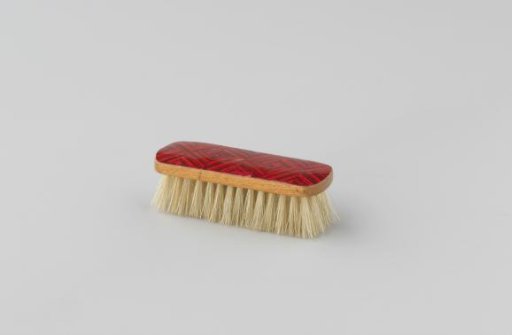 Clothing brush of wood with hair. Underside red with diamond pattern