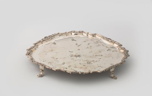 Silver presentation plate on four feet. Square with rounded corners and profile border.