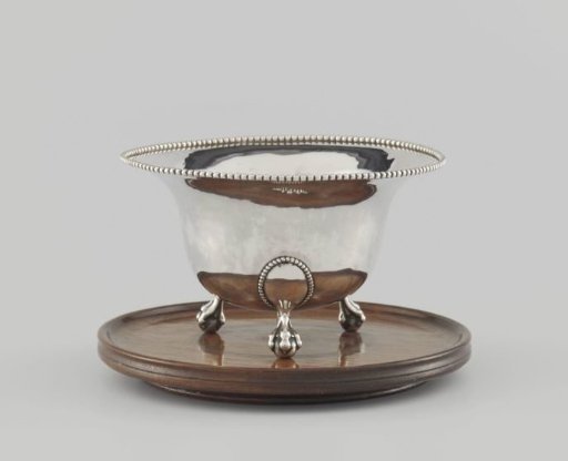 Stove of silver on three legs on a wooden top