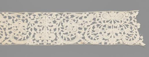 Strip of bobbin lace with two symmetrical compositions with curling leaves flanking a candelabrum motif and a bow