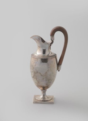 Silver milk jug, truncated egg-shaped body on a round foot with a square base, high rising neck and decorated with chased leafy vines.
