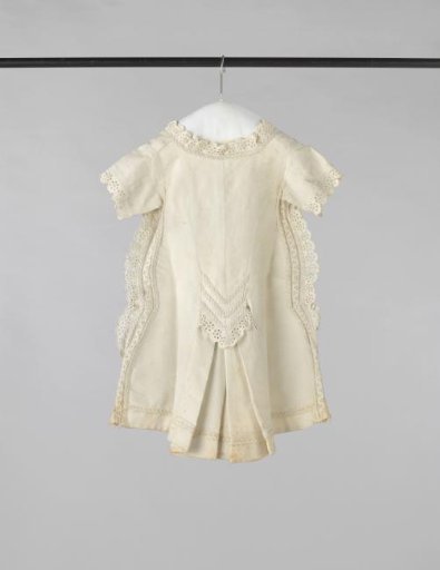 Children's dress of white cotton piqué, trimmed with an insert of passementerie and an openwork scalloped edge