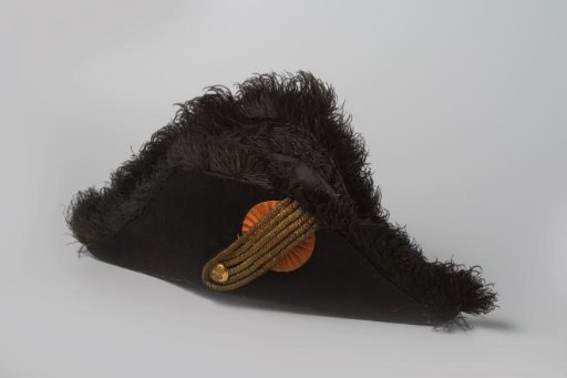 Button of black silk velvet decorated with an orange cockade, a lily of gold thread, and provided with a black ostrich feather