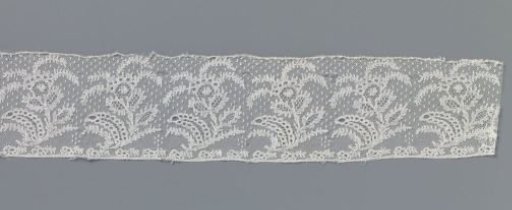 Strip of bobbin lace with flower cup from which four narrow feathered plumes spring