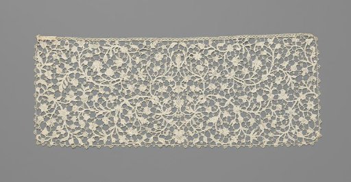 Slip of needle lace with a symmetrical pattern of thin curling vines with various flowers