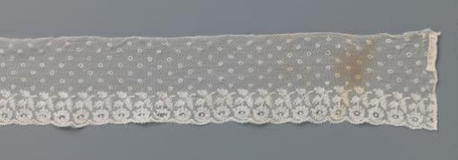 Strip of bobbin lace with scattered motifs and a border with daisies