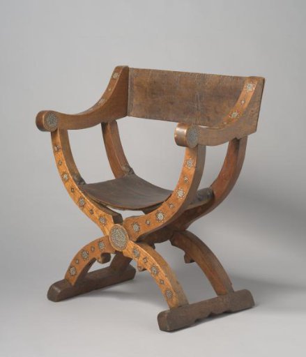 Folding chair, front view of legs, armrests and stiles inlaid with a diamond pattern alternating stars and checkerboard motifs.