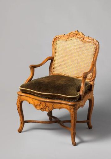Armchair of walnut and beech wood with S-shaped splayed legs; X-shaped cross with rosette; carved floral and foliate work, wicker back and seat, with loose cushion